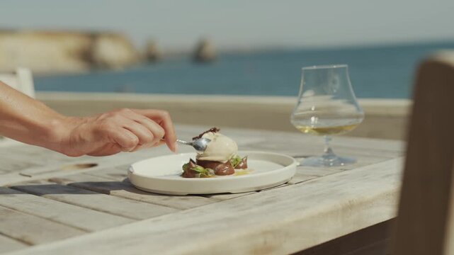 Close-up of dessert with fork and glass on wooden table near ocean