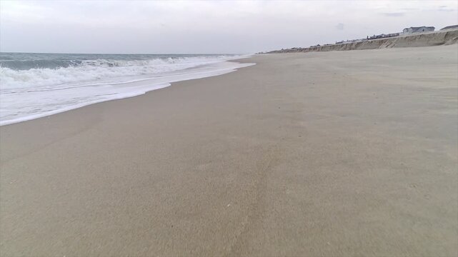 A sandy beach on the Atlantic coast. Low angle forward trucking shot.