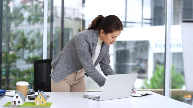 Business woman real estate agent, doing paperwork with laptop for investment strategy, review or planning.