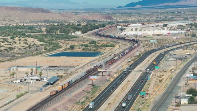 Aerial telephoto dolly shot of a freight train approaching an intermodal facility in Barstow, California. 4K