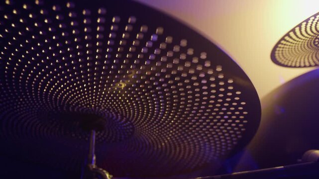 Low angle selctive focus shot of young female drummer hitting perforated cymbals during rehearsal. Ideal for music education marketing, instrument promotions, or concert advertisements
