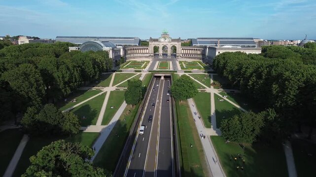 Aerial drone flight over the historic Cinquantenaire Park in Brussels featuring urban expressway traffic below.