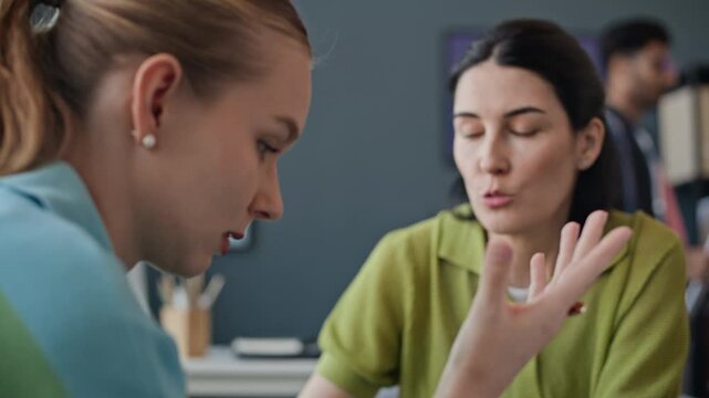 Closeup of stressed young adult Caucasian female employee crying at workplace while supportive colleague talking to her in support. Perfect for corporate mental health and workplace wellness campaigns