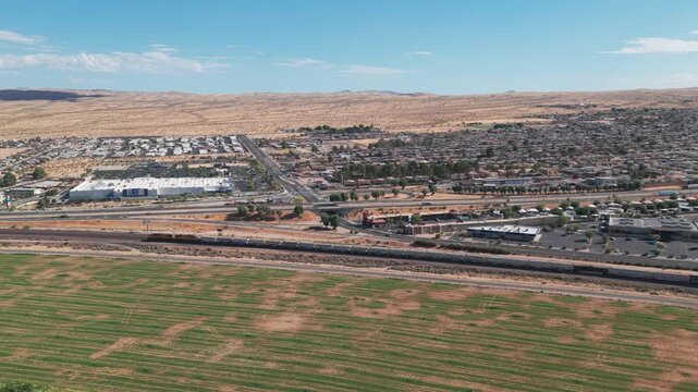 Aerial wide panning shot of a freight train along Interstate 15 in Barstow, California. 4K