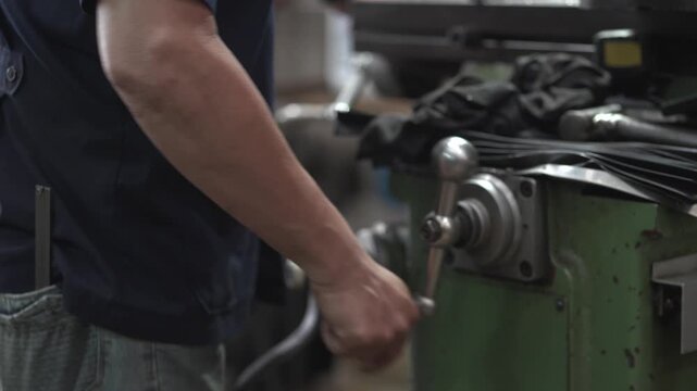 Skilled Machinist Operating Drill Press Machine in Small Community Metalworking Workshop