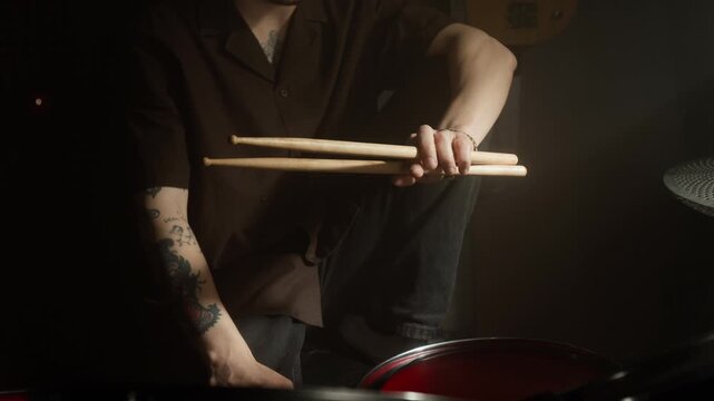 Tilt up portrait of Caucasian young man holding drumsticks in recording studio, looking directly at camera. Footage for music school promos or instrument advertisements