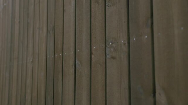 Close-up of dark vertical wooden cladding boards with visible grain, knots, and fasteners