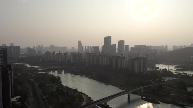 A hazy daytime city view showing a river, multiple bridges, and dense urban high-rise buildings.
