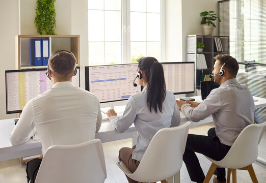 Operators agents with headsets handle call support. In a bright office staff assist customers on dual monitors for responses and clear communication. Efficient teamwork in customer service.