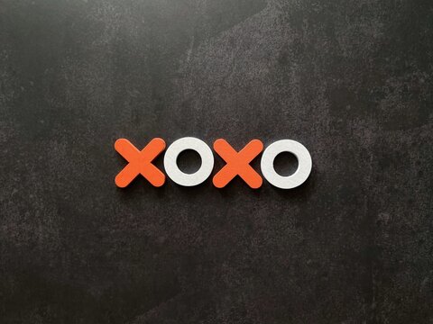 XOXO wooden letters arranged on a black background representing love, affection, romance and relationships with copy space.
