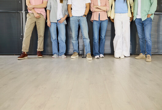 Students group on campus youth classmates standing. University education theme with cropped legs, casual jeans and footwear, floor space for copy and diversity. Teamwork and learning for youth.