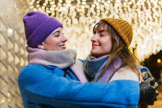 Happy lesbian couple hugging enjoying winter christmas lights