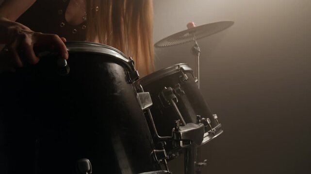 Young woman adjusting drum kit hardware and playing drums in music studio. Footage for music school advertisements, hobby promotions, or creative arts content