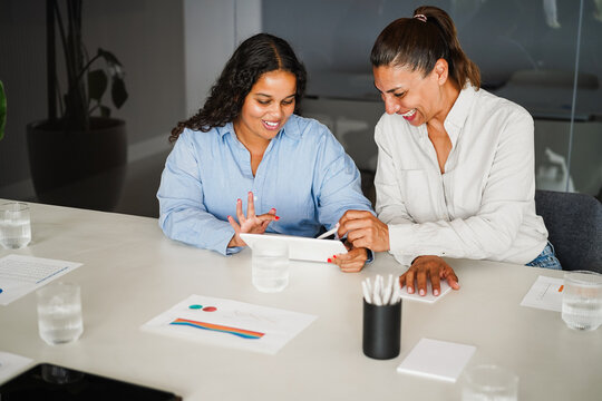 Business women sharing ideas inside company office - Females latin colleagues discussing new financial project - Brainstorming, entrepreneur and corporate concept - Main focus on left girl face