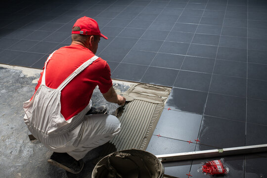 Professional Tiler Installing Large Dark Ceramic Floor Tiles