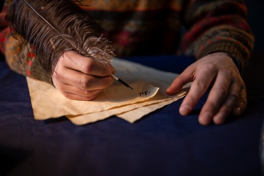 Hand of a writer writing with a feather quill