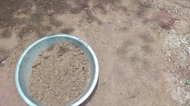 Worker digging sand and soil with a hoe tool at a construction site