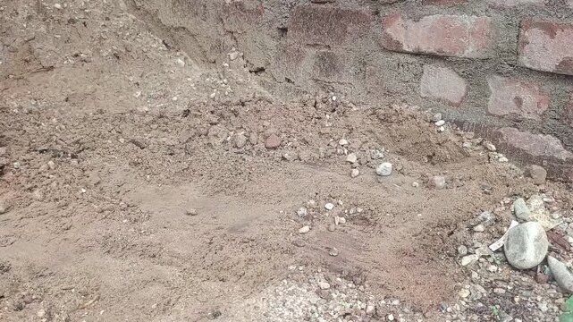 Worker digging sand and soil with a hoe tool at a construction site