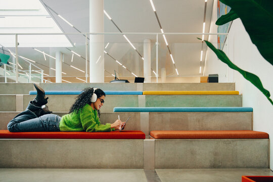 Creative postgraduate student using tablet with headphones in library
