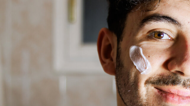 Man applying face cream, focusing on self-care and facial skin health