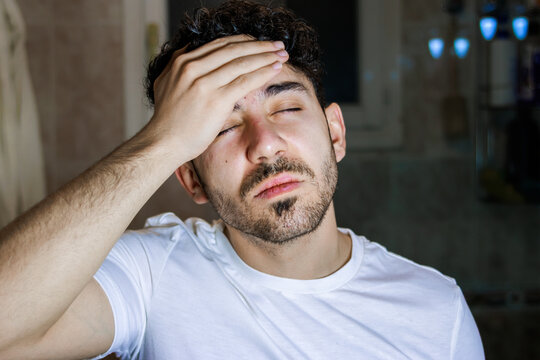 Man suffering from pain and stress, closing eyes with hand on forehead