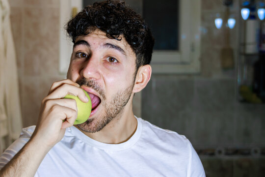 Young man eating a green apple, promoting healthy food choices and self-care