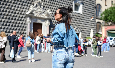 Fototapeta premium Naples,Italy, Piazza del . Gesu` nuovo.Young beautiful happy smiling woman using a mobile phone taking a pictures.Concept of Italian gastronomy and travel