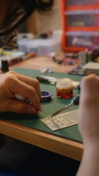 Vertical video of man soldering electronic components onto circuit board. Clip is ideal for engineering education, DIY technology tutorials, or hardware development promos