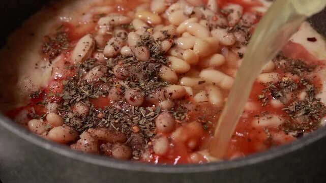 Simmering Hearty Homemade Bean Soup with Vegetables in Metal Pot on Cooktop