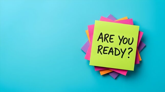 Neon green sticky note with text Are You Ready placed on top of a colorful stack of paper memo pads, isolated on a solid bright cyan table background