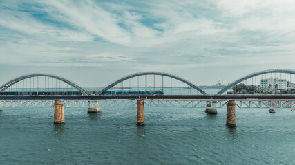 Naklejka premium Overhead view of arched railway bridge with train passing over water
