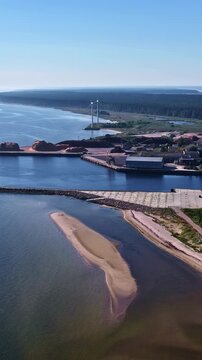 Industrial Port And Wind Turbines On Shoreline Of Salacgriva In Latvia. vertical aerial shot