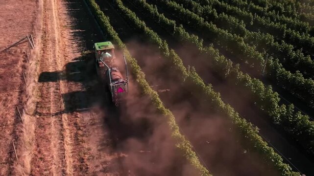 High aerial drone shot of a modern tractor working across a large agricultural field in the British countryside. Expansive farmland and precision farming machinery showcase efficient agricultural oper