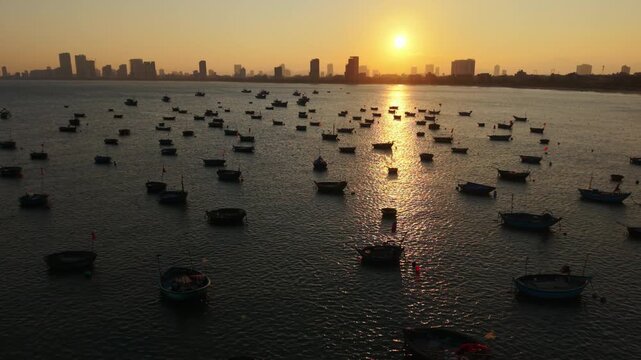Vietnam, Da Nang Da Nang Fishing Boats At Sunset, Golden Light Across Calm Bay With Dozens Of Small Round Boats Anchored, Distant City Skyline In Silhouette, Gentle Ripples And Reflective