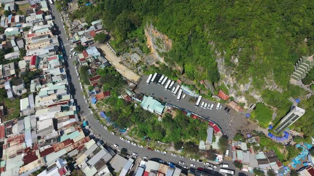 Vietnam, Da Nang Aerial View Da Nang Cliffside Bus Terminal Karst Mountain Backdrop, Line Of White Coaches Parked At Base, Drivers And Tour Operators Preparing Departures, Road Hugging Green