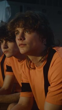 Serious Expressions of Teenage Football Squad During Post Workout Briefing. Sitting on Locker Benches, Absorb Tactical Advice and Motivational Words. Team Unity, Mental Toughness. Vertical Shot.