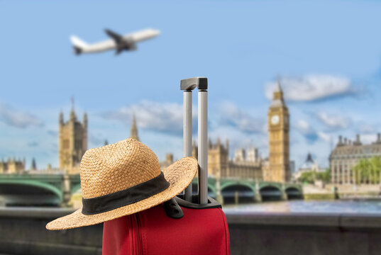 For travel and vacations purposes, a simple modern suitcase in red color and hat in London.