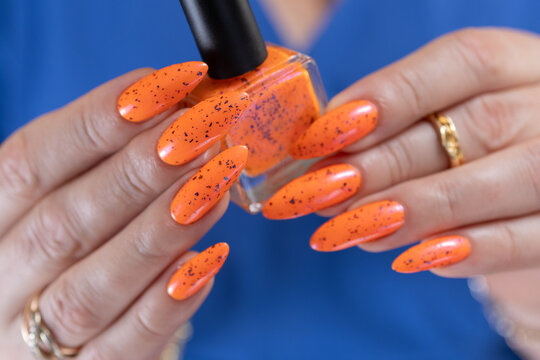 Female beautiful hand with long nails and a bright orange nail polish