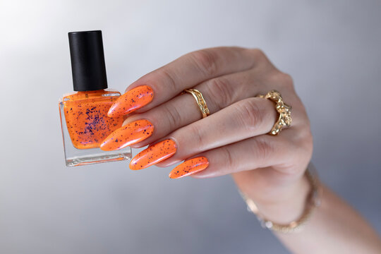 Female beautiful hand with long nails and a bright orange nail polish