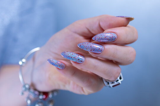 Woman hand with long nails manicure and light lilac, blue and pink nail polish