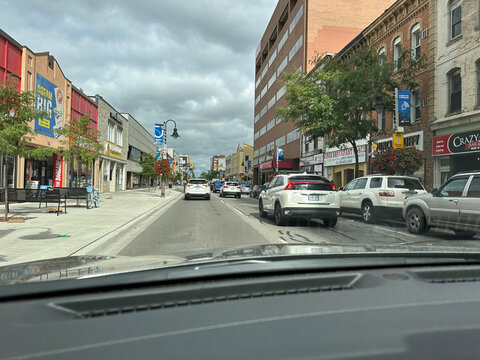 oshawa, canada - august 30 2023. shows a street with shops and cars. People walk along the sidewalks. Buildings line the street under cloudy skies.