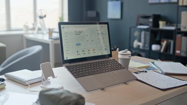 No people shot of laptop displaying business analytics dashboard in contemporary office workspace. Footage is ideal for corporate presentations, financial reports, or tech marketing