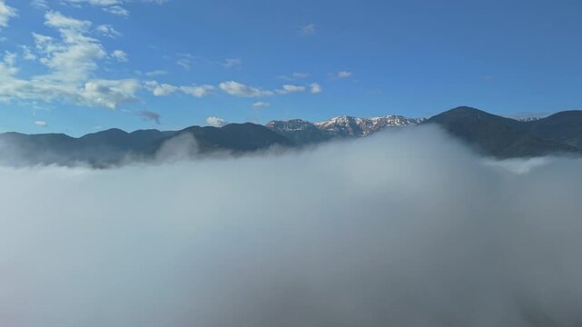Mountain peaks rising above a sea of clouds in Catalonia, Spain, aerial drone view of low fog covering valleys