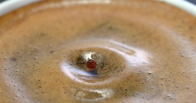 Falling drop into coffee cup, super slow motion