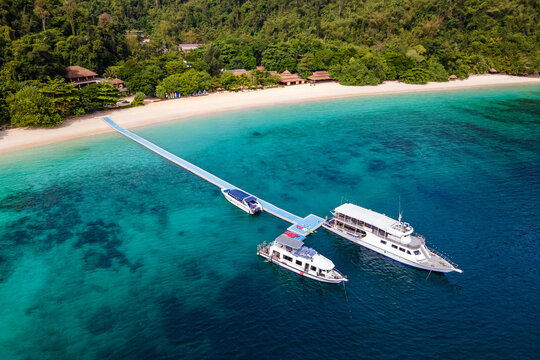 Aerial view of tour boats, speedboat with kayak board on floating jetty in front of the resort at Nyaung Oo Phee island in Myanmar. Travel attraction for summer vacation in Andaman sea of Burma.