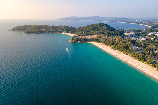 Aerial top view of Surin beach and Pansea Beach during sunset. Turquoise waves reach the Andaman sea coastline on a sunny day. Travel attractions for summer vacation in Phuket, Thailand.