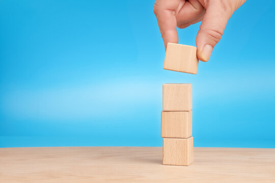 Hand stacking wooden cubes for business growth and development