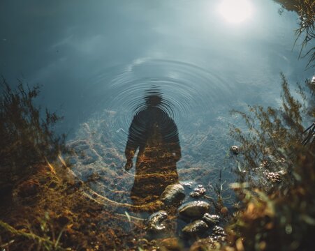 A person's reflection in a still pond, the water is crystal clear, showing a clear conscience and health