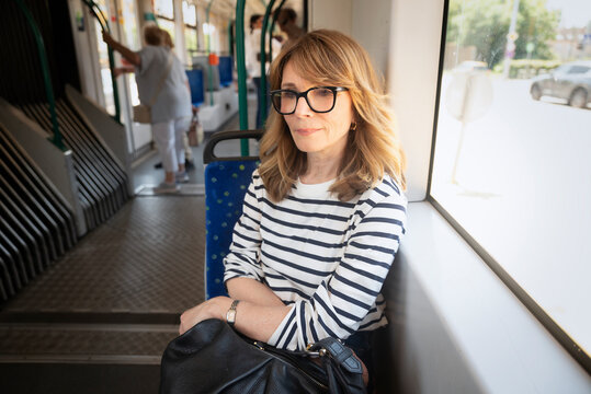 Smiling mid-aged woman on her way to home sitting in the tram