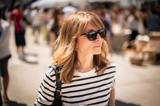 Blond haired mature woman walking at the flea market in an european city
